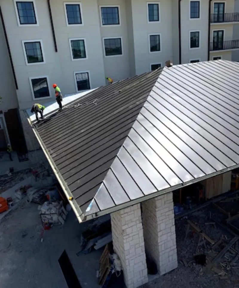 Crew installing standing seam metal roof panels on a commercial project in South Boston